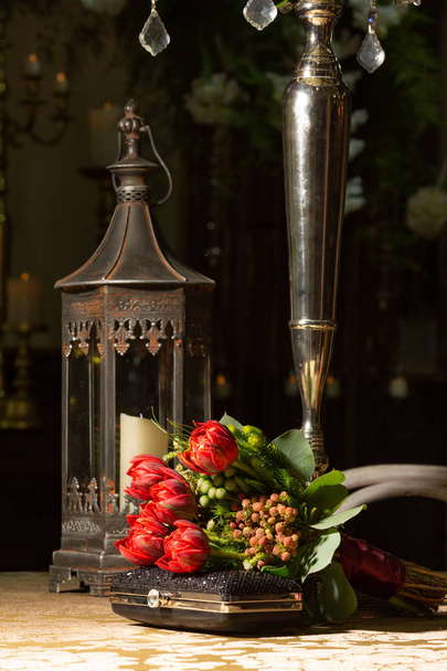 Bonito buquê de tulipa vermelha de fowers e embreagem preta na mesa formal para evento formal, casamento ou baile
. - Foto, Imagem