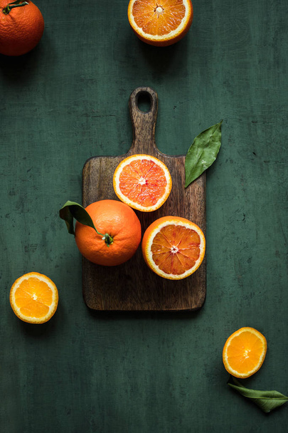 Orange fruit background. Ripe juicy oranges on cutting board. Green background top view. - Φωτογραφία, εικόνα