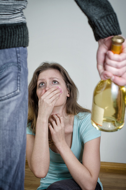 Home violence concept. Frightened woman and male hand holding bottle of wine - Photo, Image