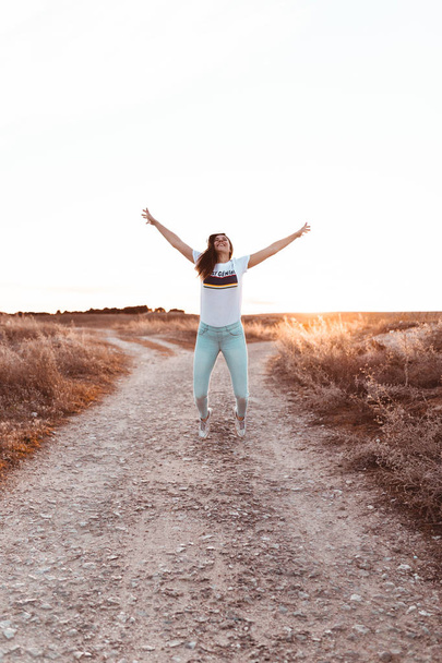 jovem mulher pulando ao pôr do sol no campo
 - Foto, Imagem