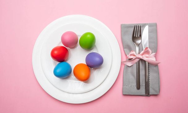 Velikonoční stůl, prostírání. Pohled shora na velikonoční vajíčka, pastelové barvy lakované v bílé desky, růžová barva pozadí, - Fotografie, Obrázek