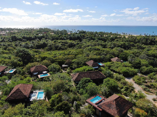 Aerial view of luxury villa with swimming pool in tropical forest. Private tropical villa with swimming pool among tropical garden with palm trees with blue sea and coast on the background. Praia de Forte, Bahia, Brazil - Photo, Image