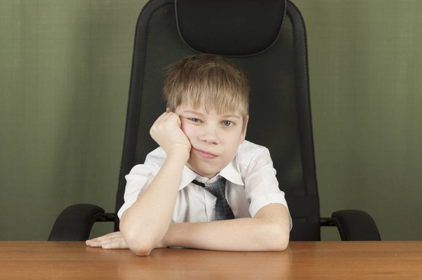 Portrait of stylish business child sitting at workplace. Cute caucasian boy imitating businessperson or office worke - 写真・画像