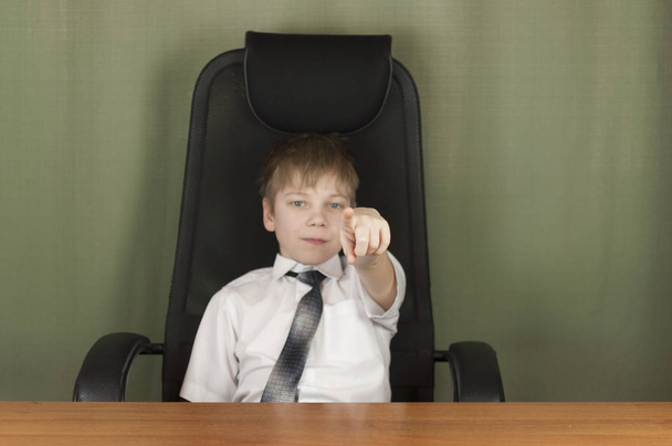 Портрет стильного делового ребенка, сидящего на рабочем месте. Милый кавказский мальчик, подражающий бизнесмену или офисному работнику
 - Фото, изображение