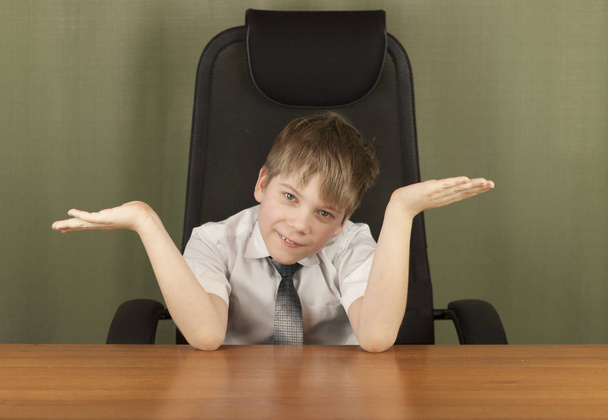 Портрет стильного делового ребенка, сидящего на рабочем месте. Милый кавказский мальчик, подражающий бизнесмену или офисному работнику
 - Фото, изображение