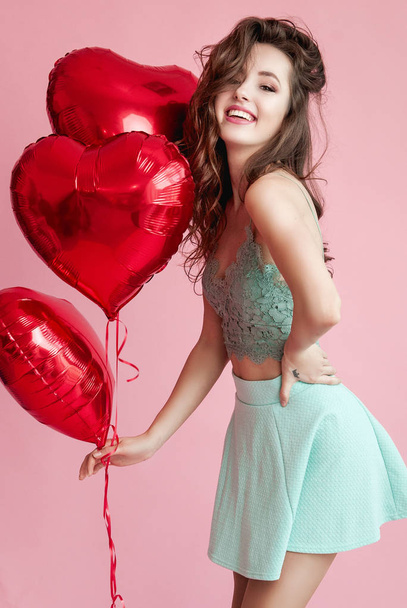 Happy beautiful young woman with red baloons over pink background. Valentines day or womans day. - Photo, Image