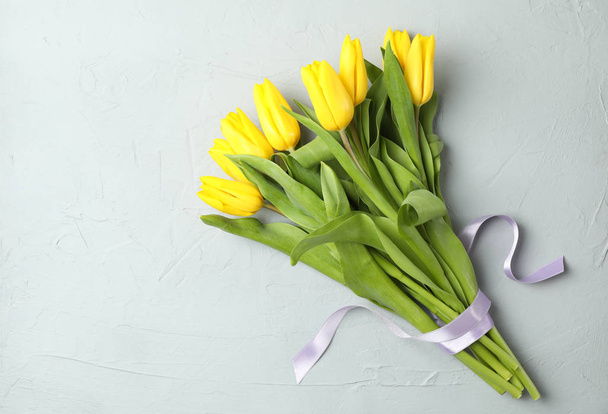 Beautiful fresh yellow tulips on gray background, top view. Space for text - Foto, Bild