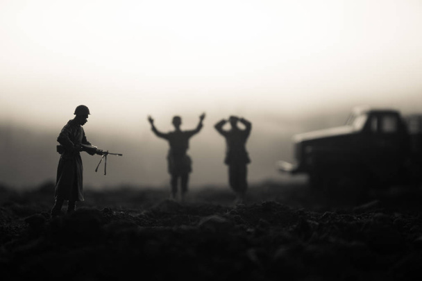 Escena de batalla. Siluetas militares peleando escena en el fondo del cielo niebla de guerra. Un soldado alemán levantó las armas para rendirse. Soldados de juguete de plástico con armas tomando prisionero al soldado enemigo. Obra de arte
 - Foto, imagen