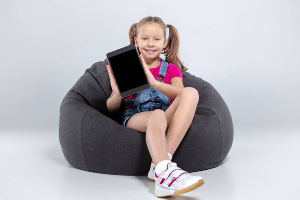 happy little schoolgirl using smartphone and listening music with headphones - Foto, afbeelding