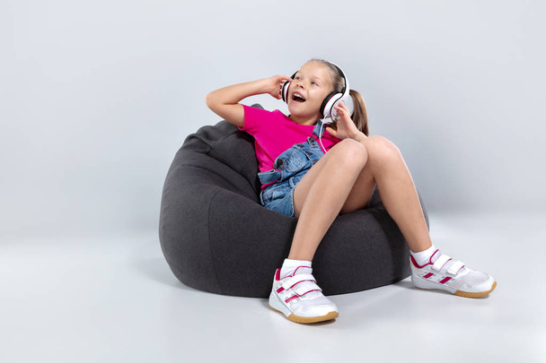 happy little schoolgirl using smartphone and listening music with headphones - Foto, immagini