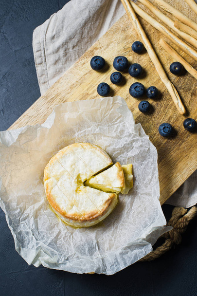 French baked Camembert with blueberries and crackers. Dark background, top view - Fotó, kép