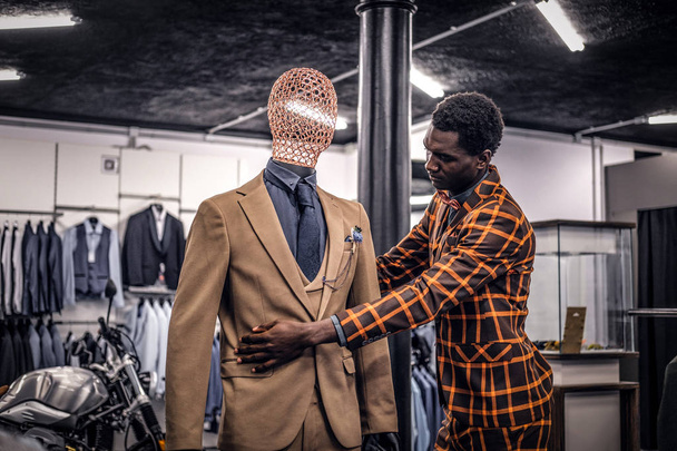 Afro-Amerikaanse man, gekleed in trendy elegante pak, werken bij klassieke herenkleding winkel. - Foto, afbeelding