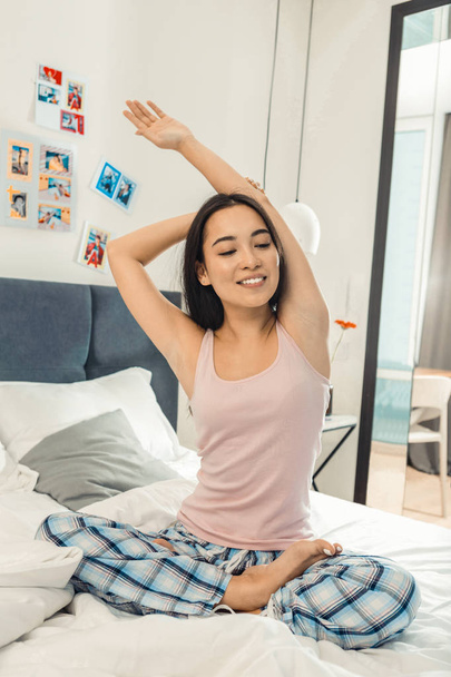 Dark-eyed Asian woman smiling while enjoying morning yoga - 写真・画像