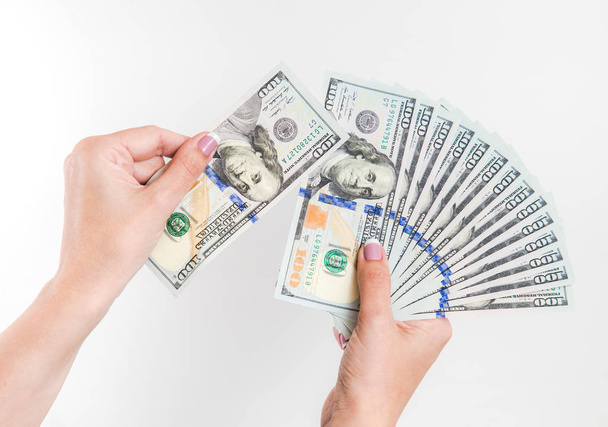 Closeup up van witte vrouwelijke handen met vele 100 dollars papieren facturen geïsoleerd op een witte achtergrond. Horizontale kleurenfotografie. - Foto, afbeelding