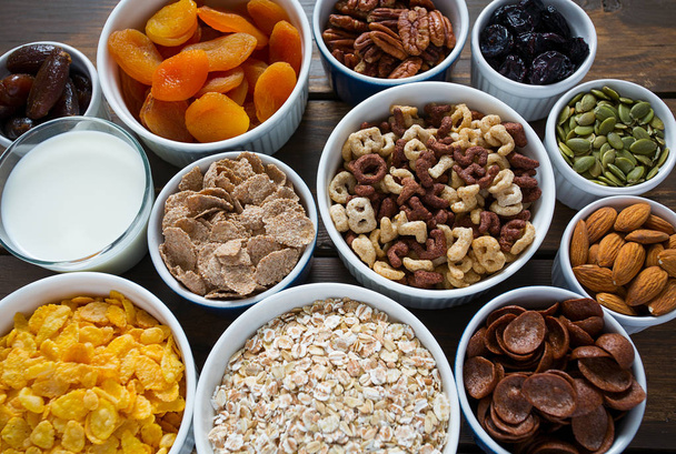 various cereals, nuts and dried fruits on wooden surface - Foto, afbeelding