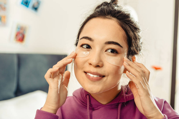 Close up of dark-eyed Asian woman taking care of her skin - Фото, зображення
