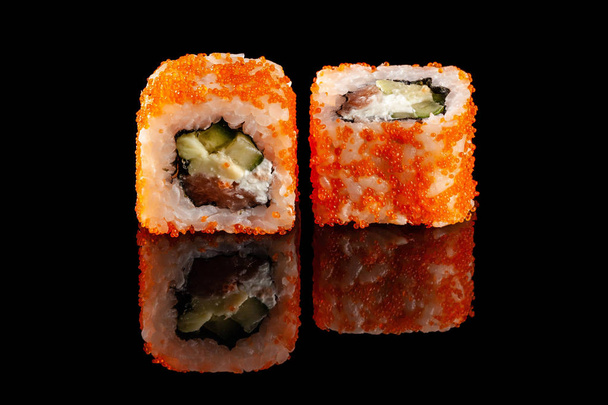 Concept of Asian cuisine. Two rolls of sushi with different fillings on a black background with the age for a Japanese menu for a cafe, restaurant, sushi bar. - Foto, Imagem