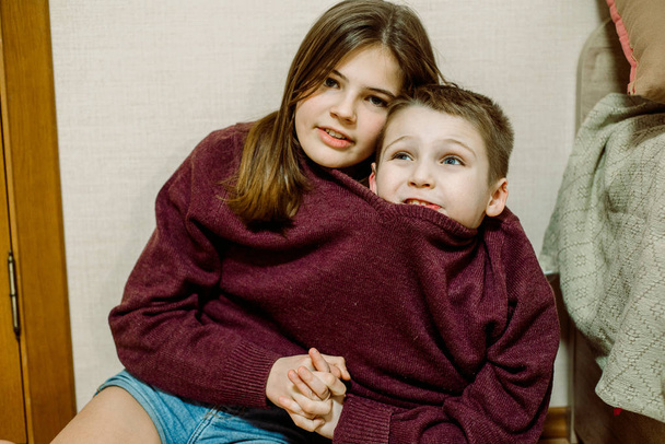 the kids are joking, one sweater for two, laughing and dabbling. Brother and sister are funny. Fool's day concept - Foto, Imagen