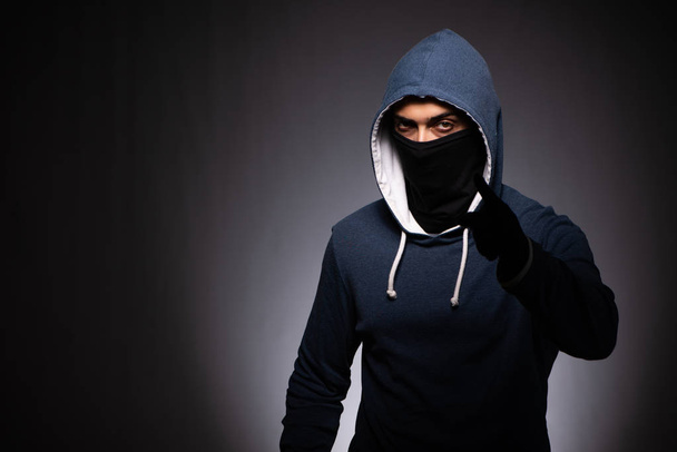 Молодой бандит в капюшоне на сером фоне
 - Фото, изображение