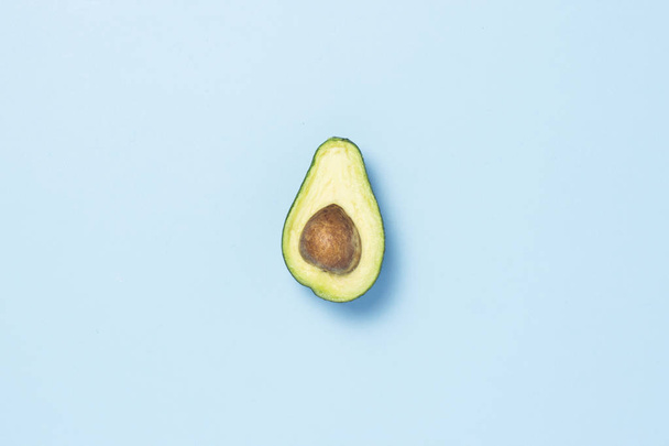 Half avocado on a blue background. Healthy eating concept. Minimalism. Flat lay, top view - Фото, зображення