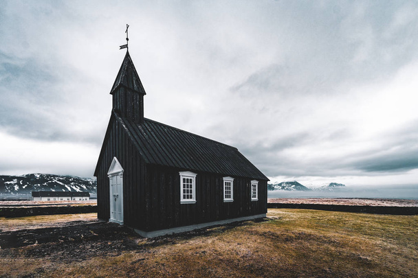 Famous picturesque black church of Budir at Snaefellsnes peninsula region in Iceland during a heavy snowy weather - Fotó, kép