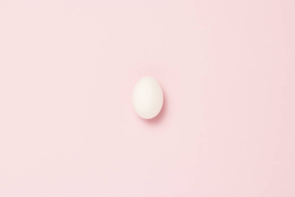 White egg on a pink background. The concept of life insurance, health and property, waiting for the birth of a child. Minimalism. Flat lay, top view - Photo, Image