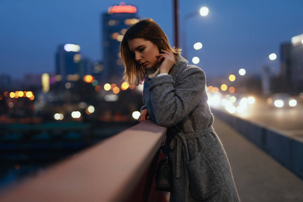 Woman standing on bridge in the ligths of the night city and thinking about future - Fotografie, Obrázek