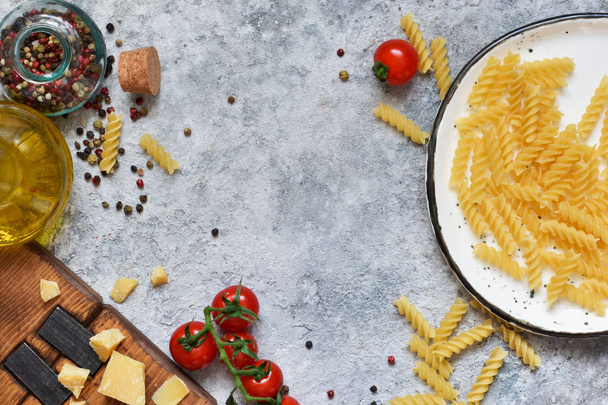 イタリア料理の背景。パスタ、トマト、パルメザン チーズ、コンクリート背景にスパイス。調理のための成分. - 写真・画像