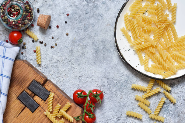 Italian food background. Pasta, tomatoes, parmesan and spices on a concrete background. Ingredient for cooking. - Fotó, kép