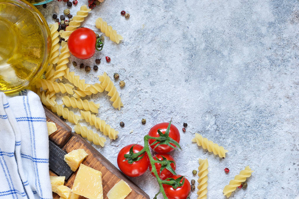 Italian food background. Pasta, tomatoes, parmesan and spices on a concrete background. Ingredient for cooking. - Fotoğraf, Görsel