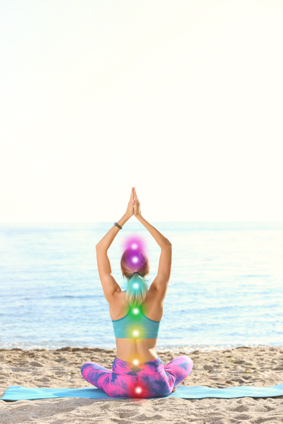 Jeune femme avec des points de chakra pratiquant le yoga zen sur la plage
 - Photo, image