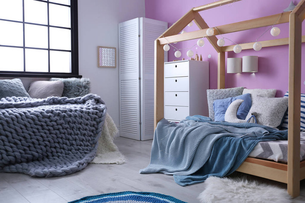 Child's room interior with comfortable bed and garland - Foto, afbeelding