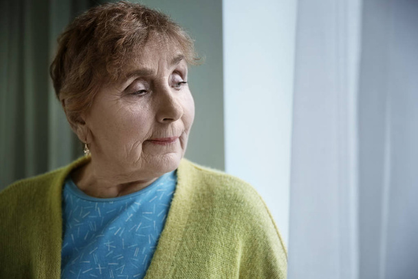Portrait of elderly woman near window indoors. Space for text - Valokuva, kuva
