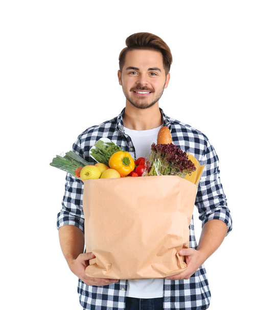 Young man holding paper bag with products on white background. Food delivery service - Zdjęcie, obraz
