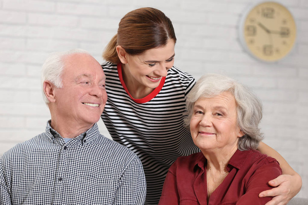 Elderly couple with female caregiver at home - Foto, afbeelding
