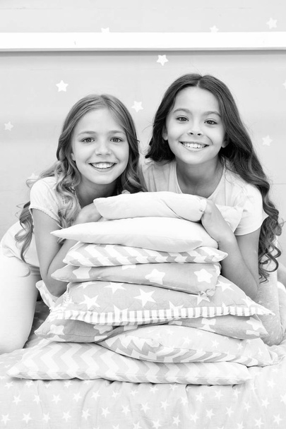 Girls best friends gather in bedroom for slumber party. Domestic party for kids. Girls near pile pillows posing with brilliant smiles. Lets start this party. Kids in pajamas prepare bedroom for party - Фото, зображення