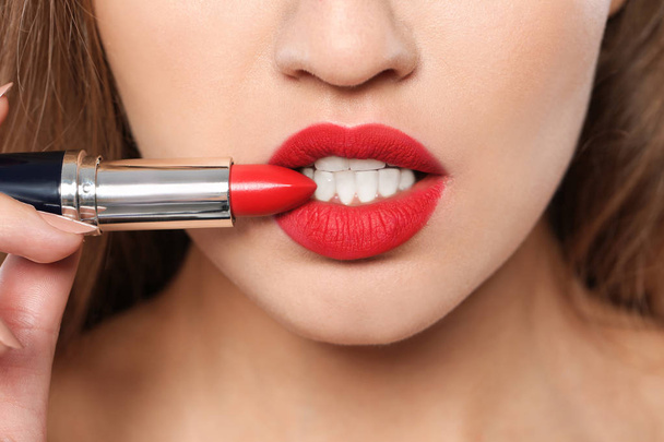 Young woman holding red lipstick, closeup view - 写真・画像