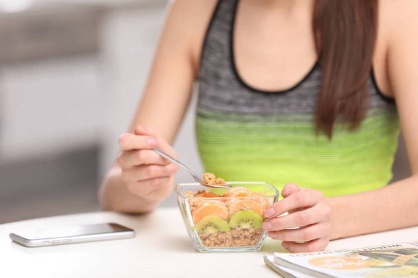 Young woman in fitness clothes having healthy breakfast at home, closeup - 写真・画像