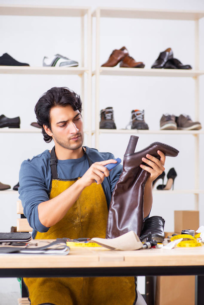 Young man repairing shoes in workshop - Фото, зображення