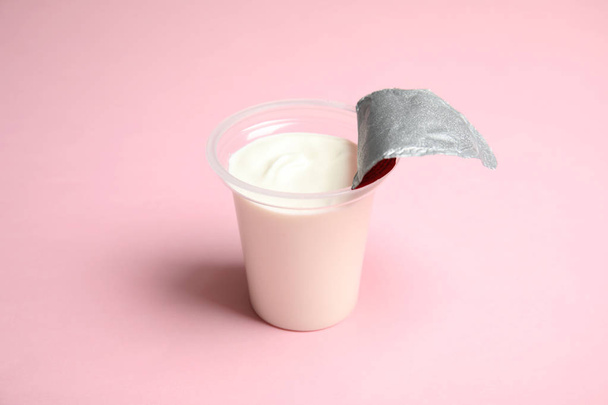 Plastic cup with creamy yogurt on color background - Foto, imagen