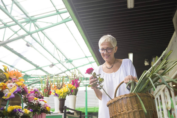 Charrming senior woman buying  flowers on local market - Foto, afbeelding