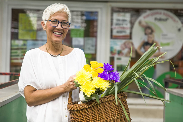 Charrming senior woman buying  flowers on local market - Photo, Image