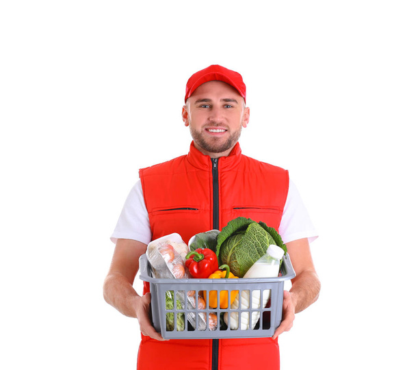 Delivery man holding wooden crate with food products on color background - Zdjęcie, obraz