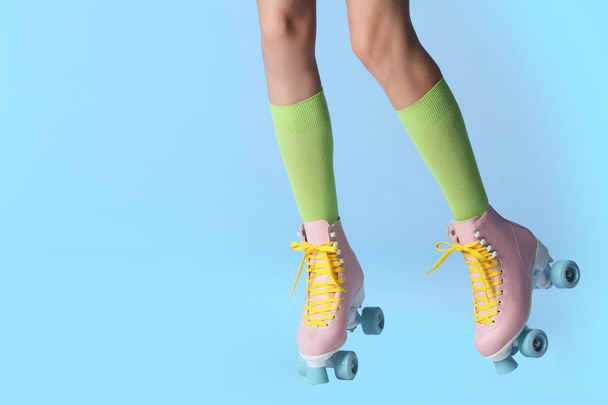 Woman with vintage roller skates on color background, closeup. Space for text - 写真・画像