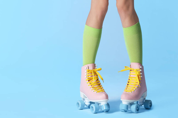 Woman with vintage roller skates on color background, closeup. Space for text - Zdjęcie, obraz