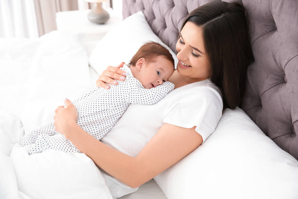 Happy woman with her cute baby on bed - Foto, afbeelding