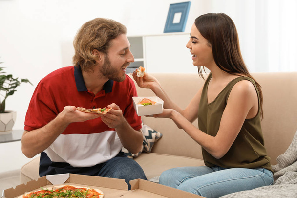 Young couple having lunch in living room. Food delivery - Foto, Imagen