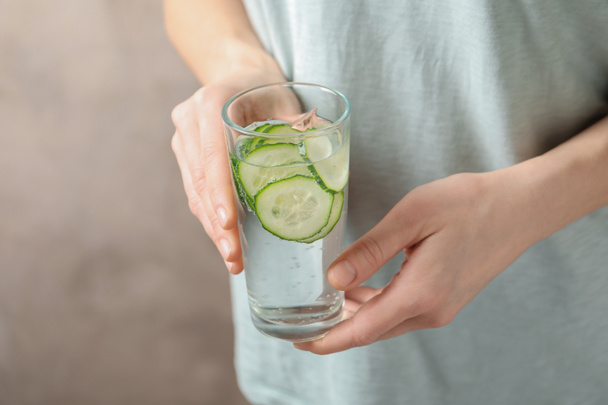 Young woman holding glass with fresh cucumber water, closeup. Space for text - Photo, image