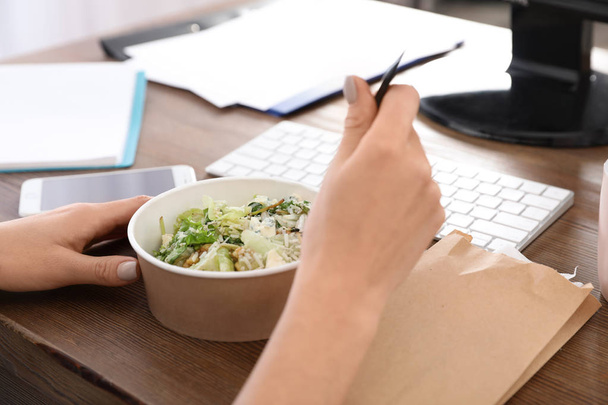 Office employee having salad for lunch at workplace, closeup. Food delivery - Foto, Bild