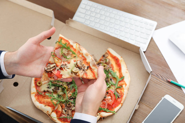 Office employee having pizza for lunch at workplace, closeup. Food delivery - Foto, Imagem
